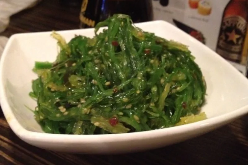 Salată de alge marine wakame într-un bol alb, presărată cu semințe de susan