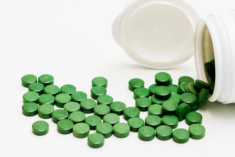 Pulbere verde de chlorella și tablete de chlorella pe o masă de lemn