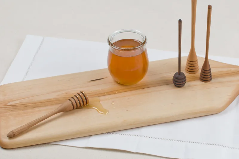 Jar of Manuka honey with a wooden honey dipper