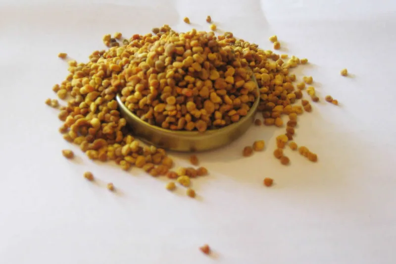 Granule colorate de polen de albine într-un vas mic