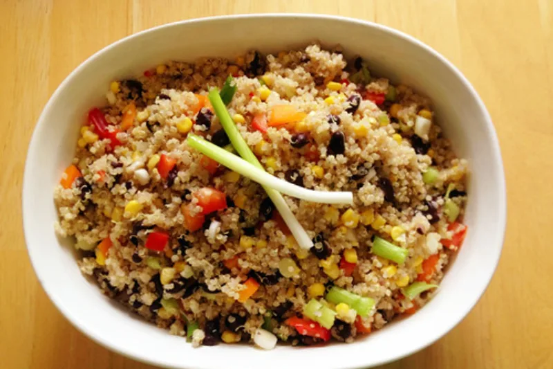 Bol cu quinoa fiartă și legume colorate pe o masă de lemn