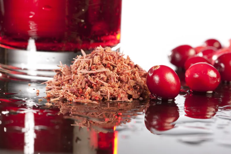 Fresh red cranberries beside a glass of red cranberry beverage
