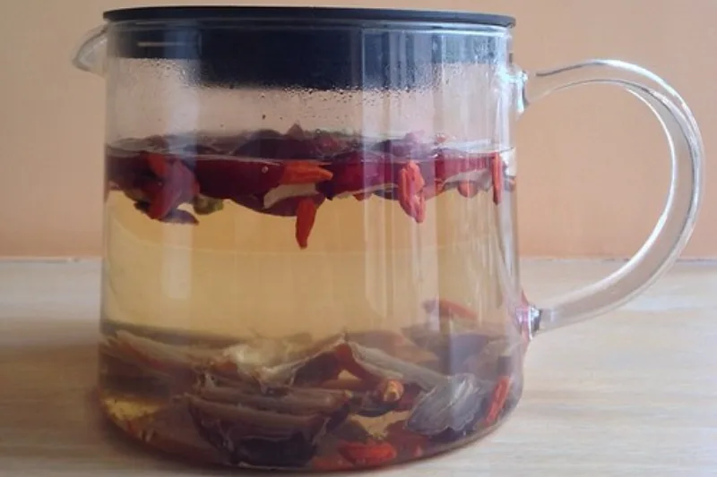 Glass cup of hawthorn berry tea with red berries steeping