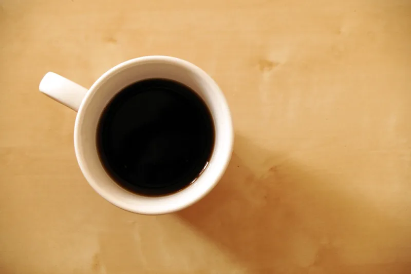 Cup of dark, hot pu-erh tea on a wooden table