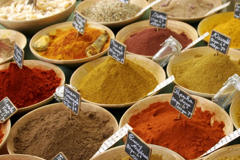 Golden yellow curry powder in a wooden bowl, surrounded by spices