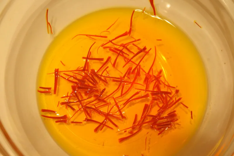 Red saffron threads steeping in a bowl of golden water