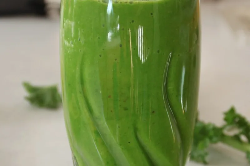 Glass of green detox juice with fresh spring herb leaves