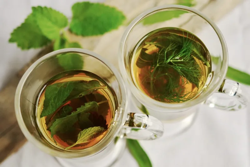Glass of water with herbs prepared for a gargle to ease a sore throat