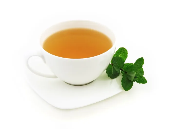 Cup of warm herbal infusion with fresh mint leaves, for respiratory steam inhalation