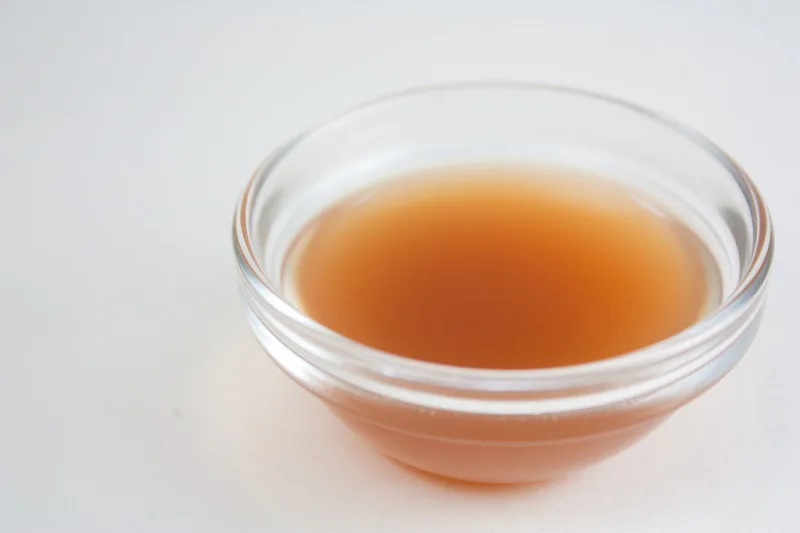 Glass bowl of natural amber apple cider vinegar used in a beauty routine
