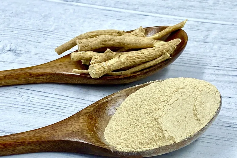 Powders and roots of adaptogenic herbs such as ashwagandha on wooden spoons