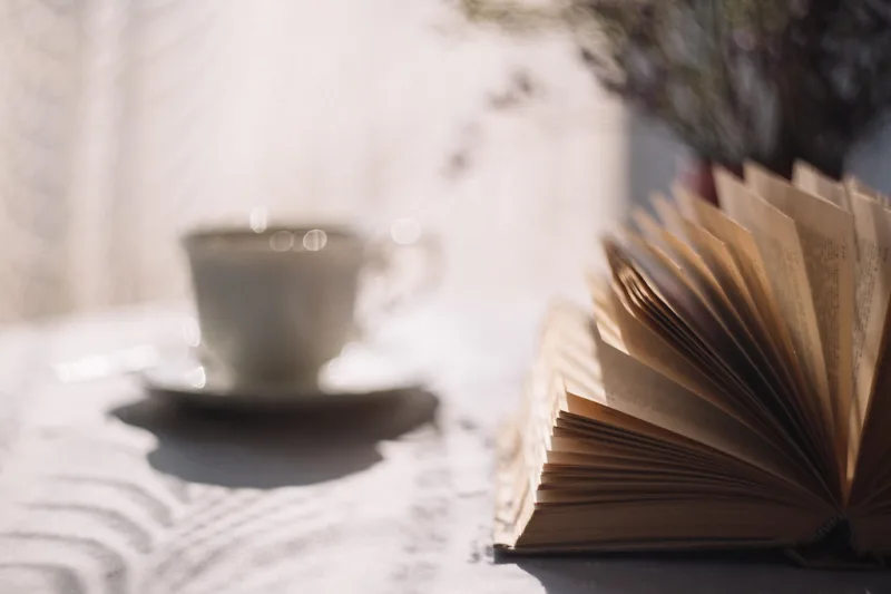 Herbal tea, books and a notebook on a study desk, suggesting focus
