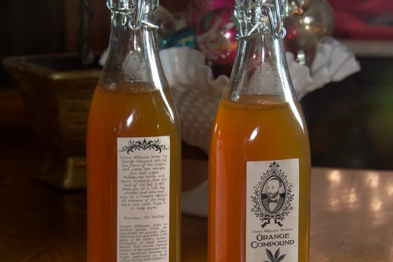 Bottles of homemade herbal syrup with golden liquid on a wooden table