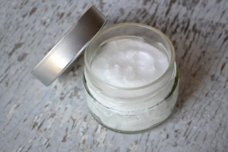 A jar of virgin cold-pressed coconut oil with a fresh coconut beside it