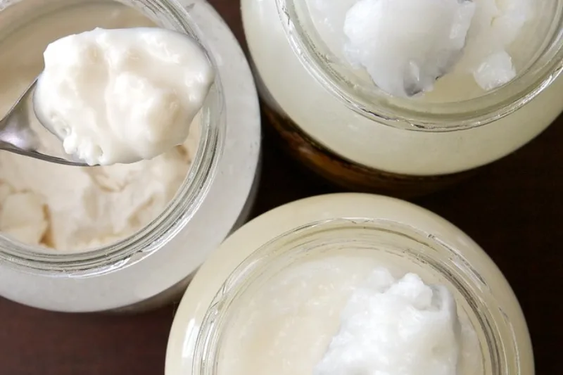 Jar of solid white coconut oil with a fresh coconut beside it