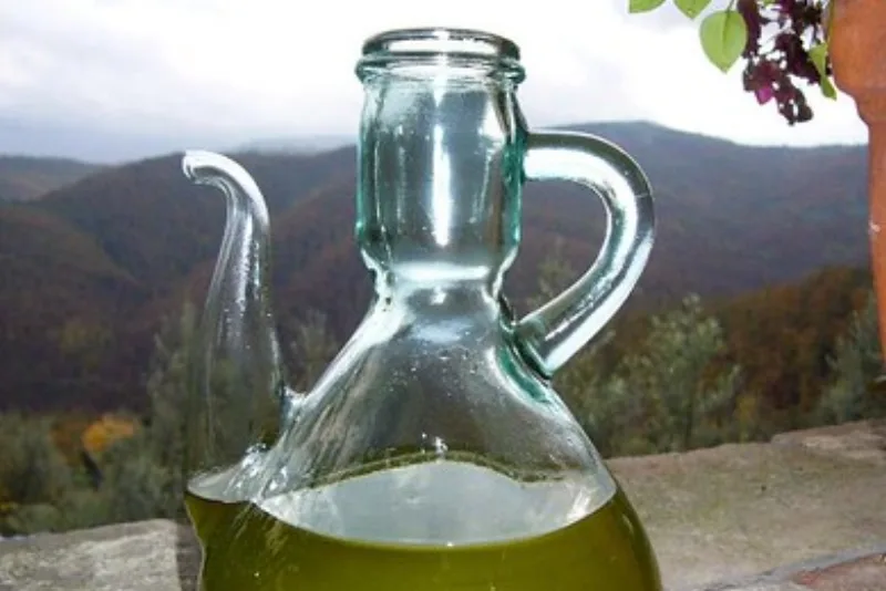 Glass cruet of golden-green olive oil on a stone parapet